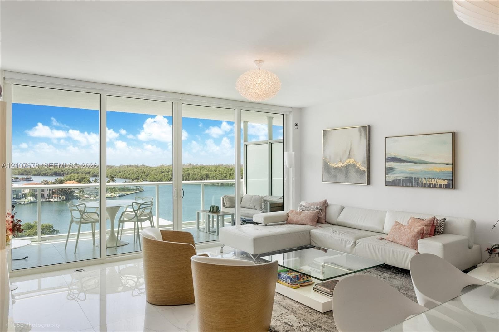Floor-to-ceiling glass sliding doors, private balcony with metal railing, polished stone-finish flooring, and pendant lighting