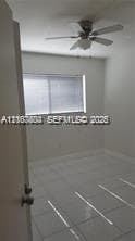 Neutral wall finishes, large-format tile flooring, window with horizontal blinds, and ceiling-mounted fan