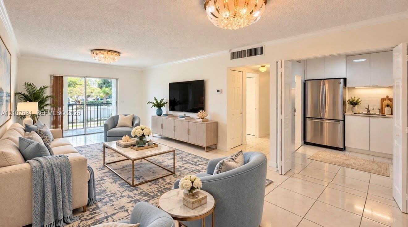 Open-concept floor plan featuring large-format tile flooring, recessed kitchen cabinetry with a clean finish, stainless steel refrigerator, and glass sliding doors leading to an exterior balcony