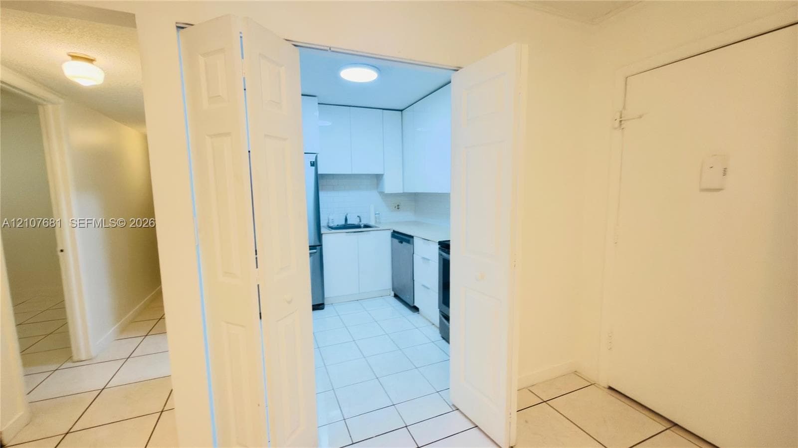 Kitchen featuring flat-panel white cabinetry, stainless steel appliances, neutral countertops, and ceramic tile flooring