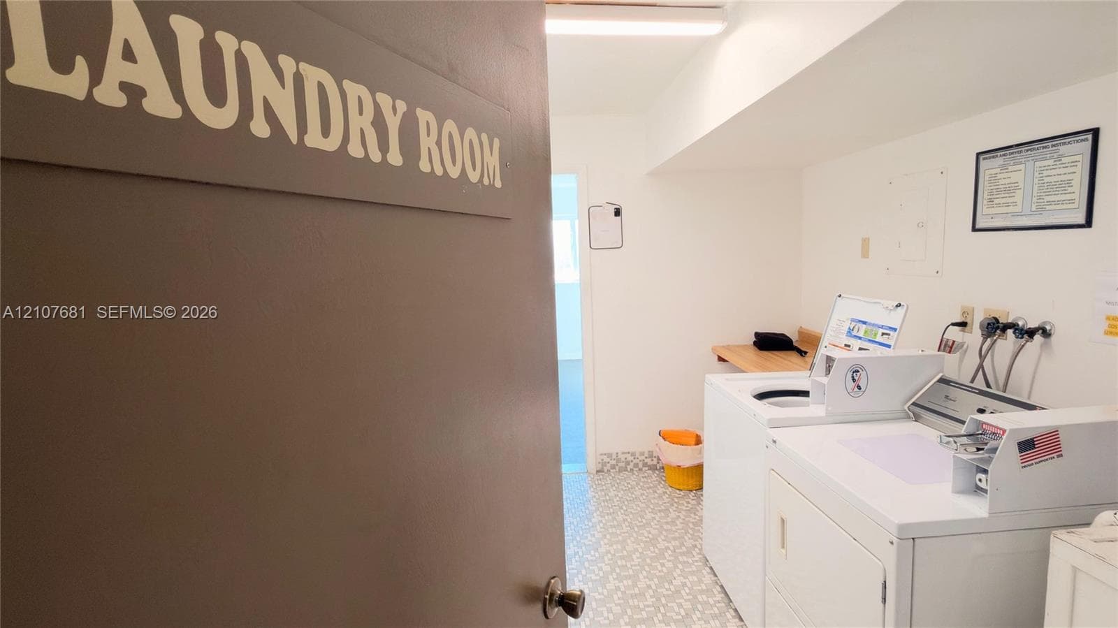Laundry room featuring patterned resilient flooring, overhead lighting, and a built-in wooden folding counter