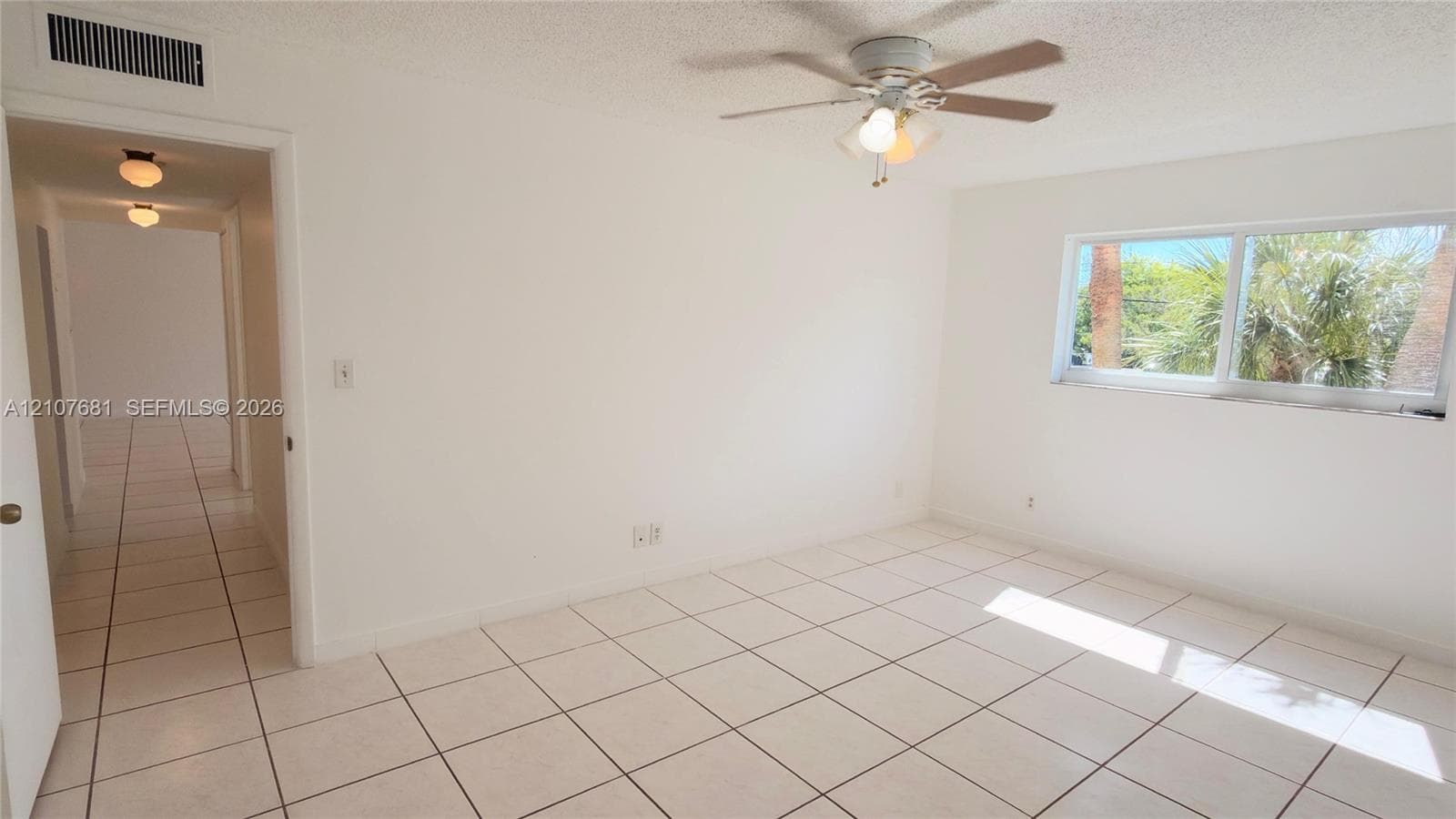 Interior space featuring large-format tile flooring, a multi-blade ceiling fan with integrated lighting, and a wide sliding window