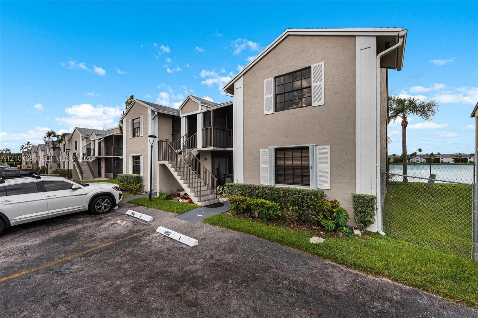 Multi-level building exterior featuring stucco siding, screened balconies, metal staircases, and grid-patterned windows