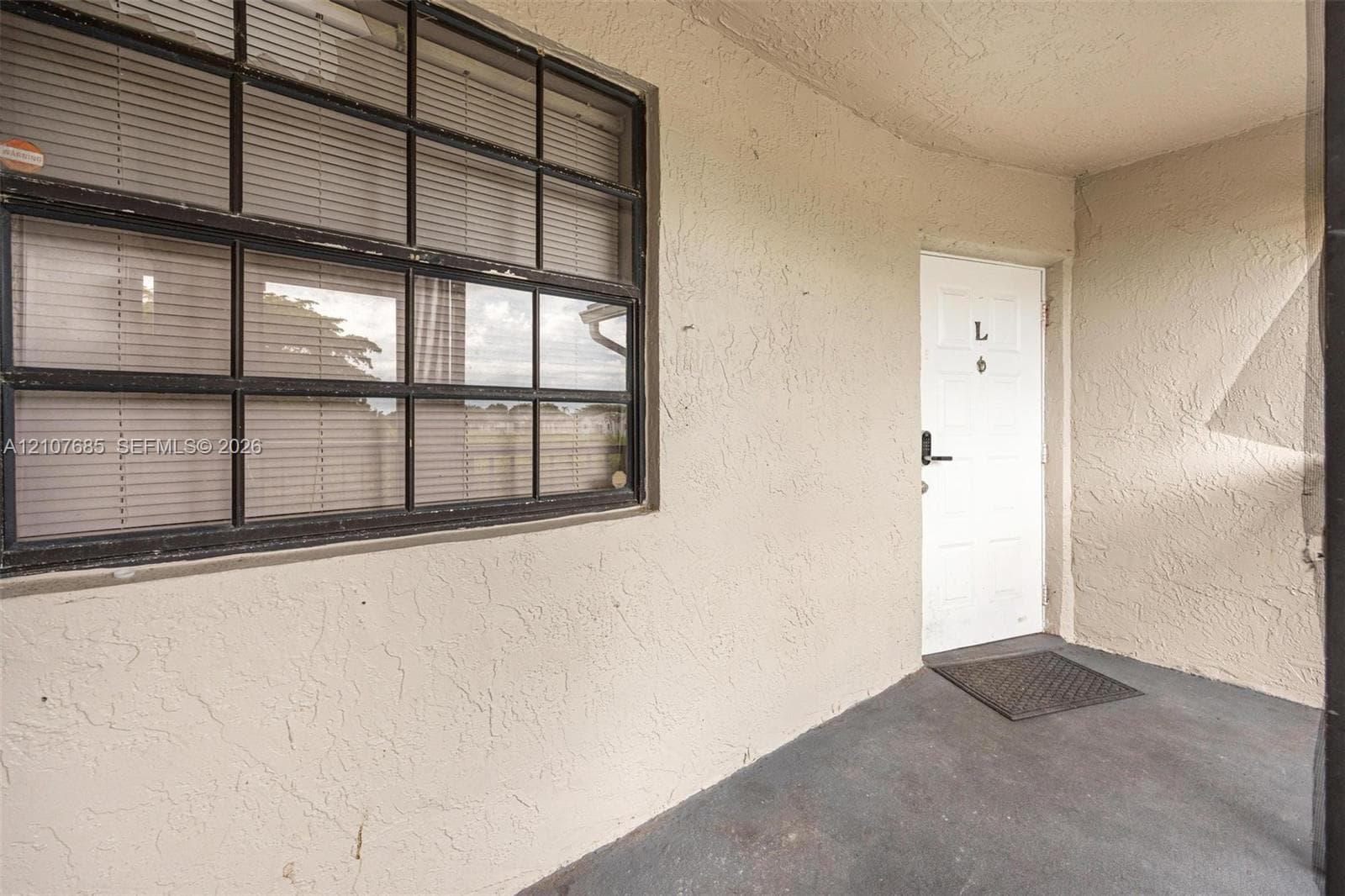 Covered entry featuring a textured stucco exterior, a single-pane glass door with a hardware lever, and a multi-lite window with a dark frame