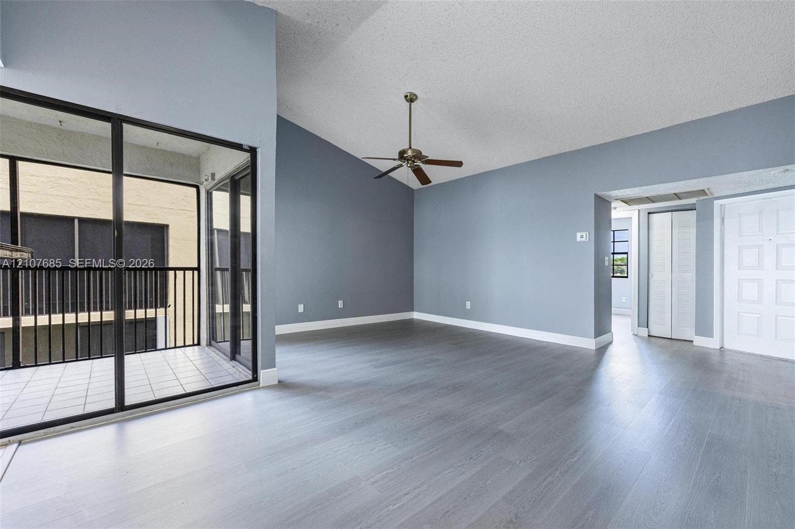 Vaulted ceilings, wood-finish flooring, ceiling fan, and sliding glass doors with direct access to a private balcony