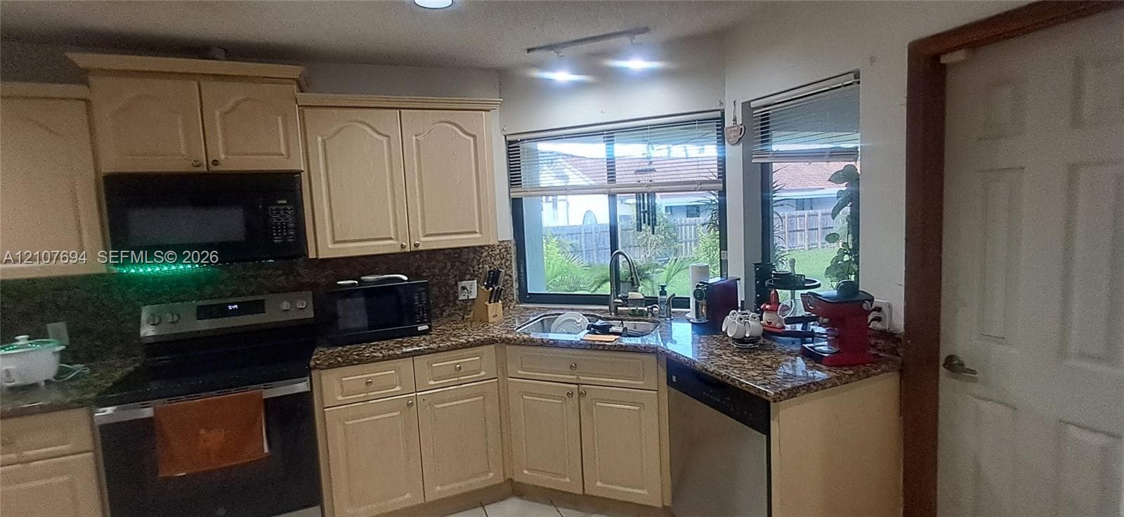 Kitchen featuring raised-panel cabinetry, stone-surface countertops, built-in microwave, integrated stainless steel appliances, and dual-pane windows