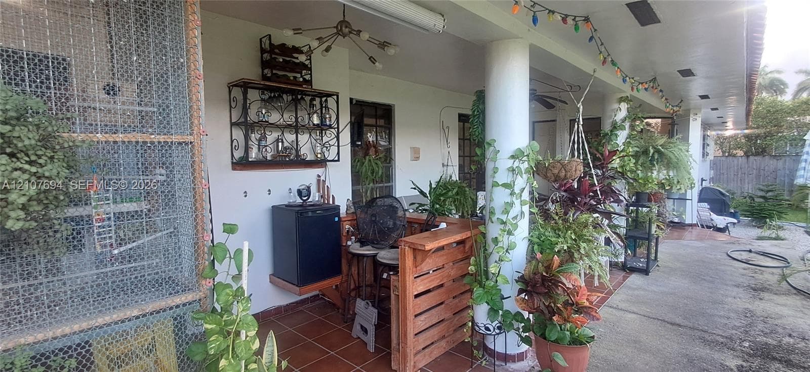 Covered patio featuring tiled flooring, structural columns, and a custom built-in wooden bar unit