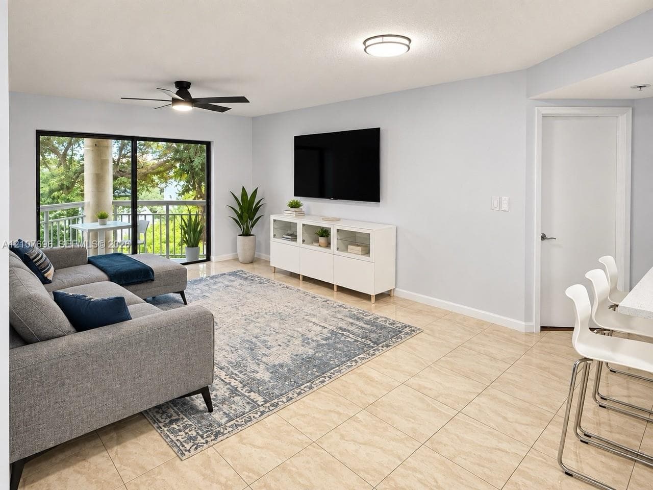Neutral-tone large-format tile flooring, recessed overhead lighting, matte black ceiling fan, and sliding glass doors with balcony access