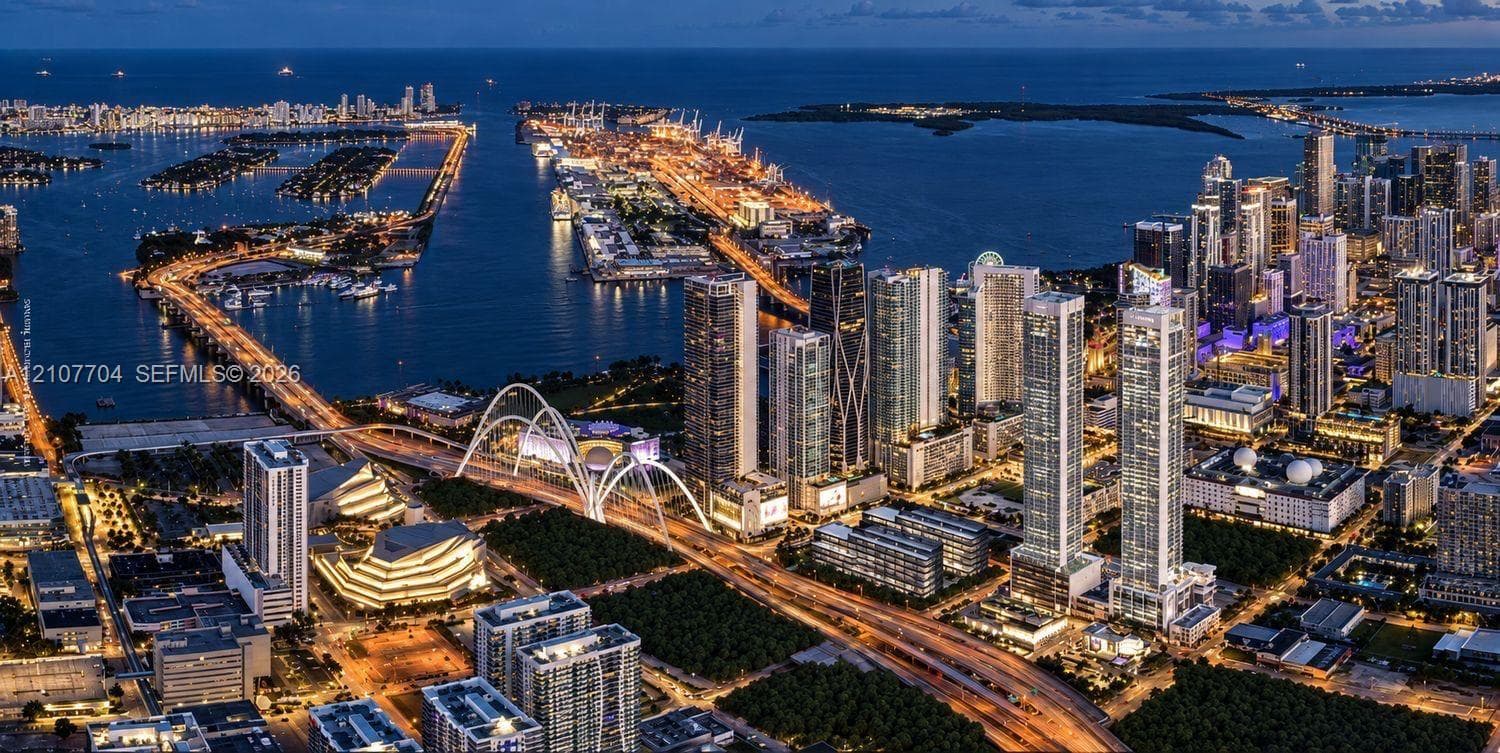 Aerial perspective of a metropolitan skyline featuring high-rise architecture, proximity to a coastal waterway, complex bridge infrastructure, and dense urban development