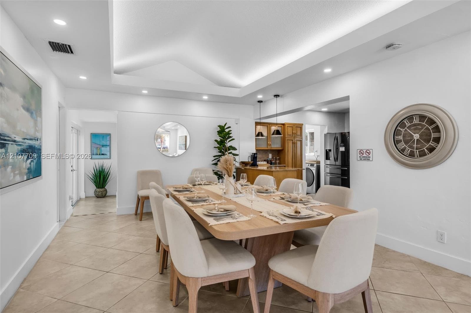 Tray ceiling with recessed lighting, tile flooring, and custom wood cabinetry