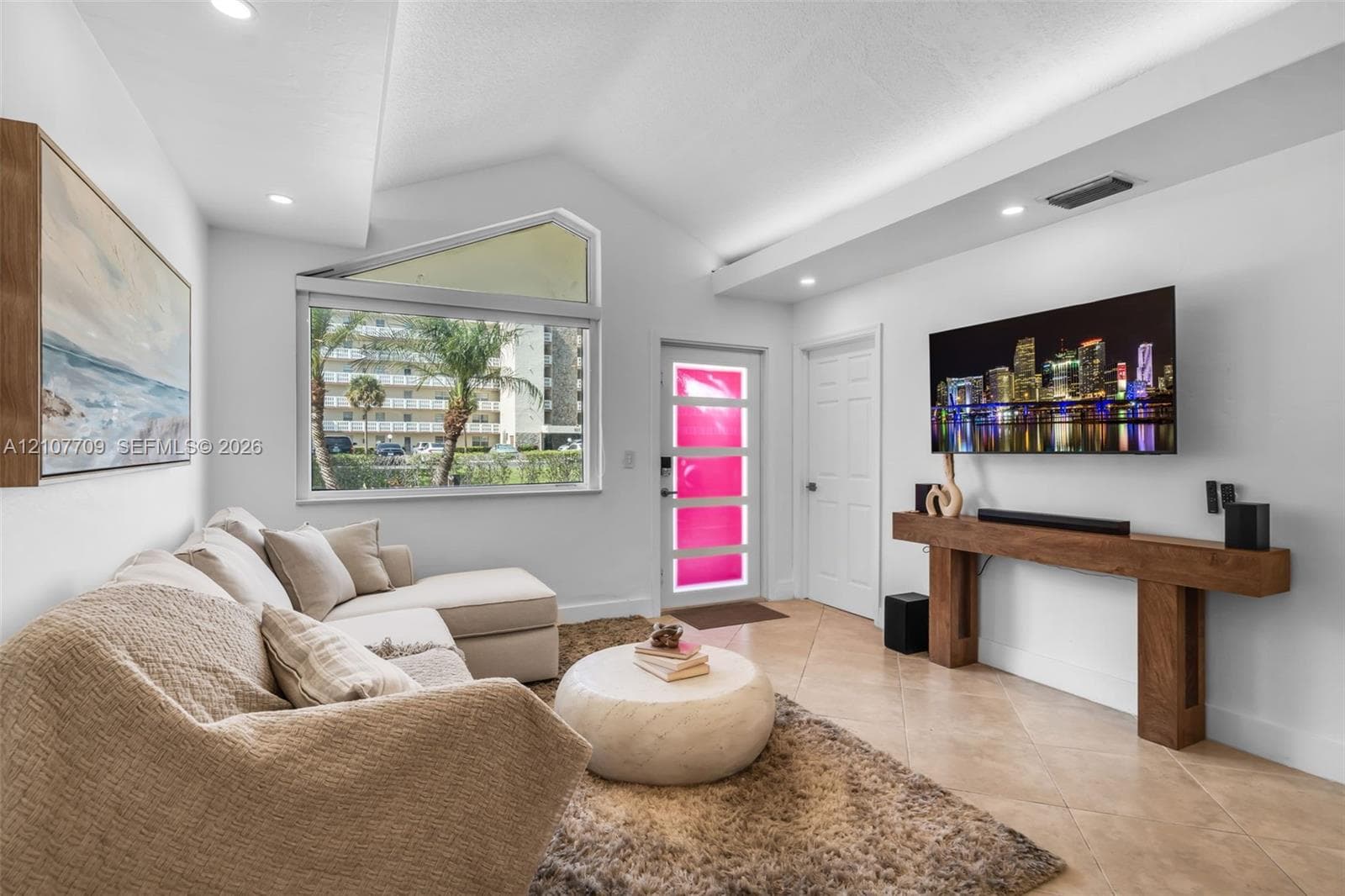 Vaulted ceiling, geometric transom window, tile flooring, and custom wall-mounted wood console