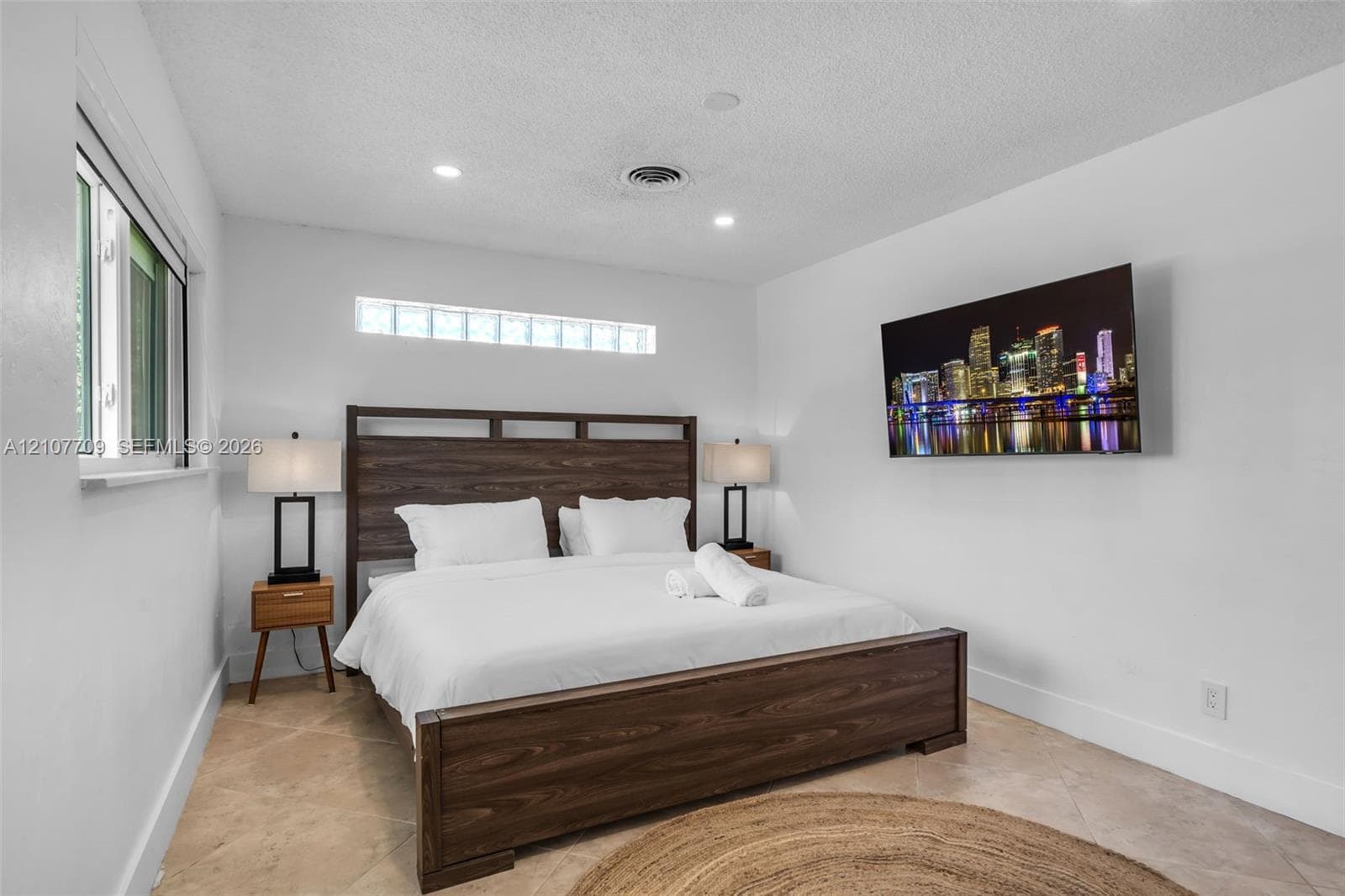 Room featuring light-toned tile flooring, recessed lighting, and a horizontal glass block window