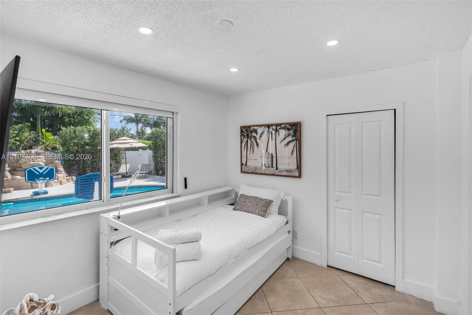 Interior room featuring large-format tile flooring, recessed ceiling lighting, and a wide window with a pool backdrop