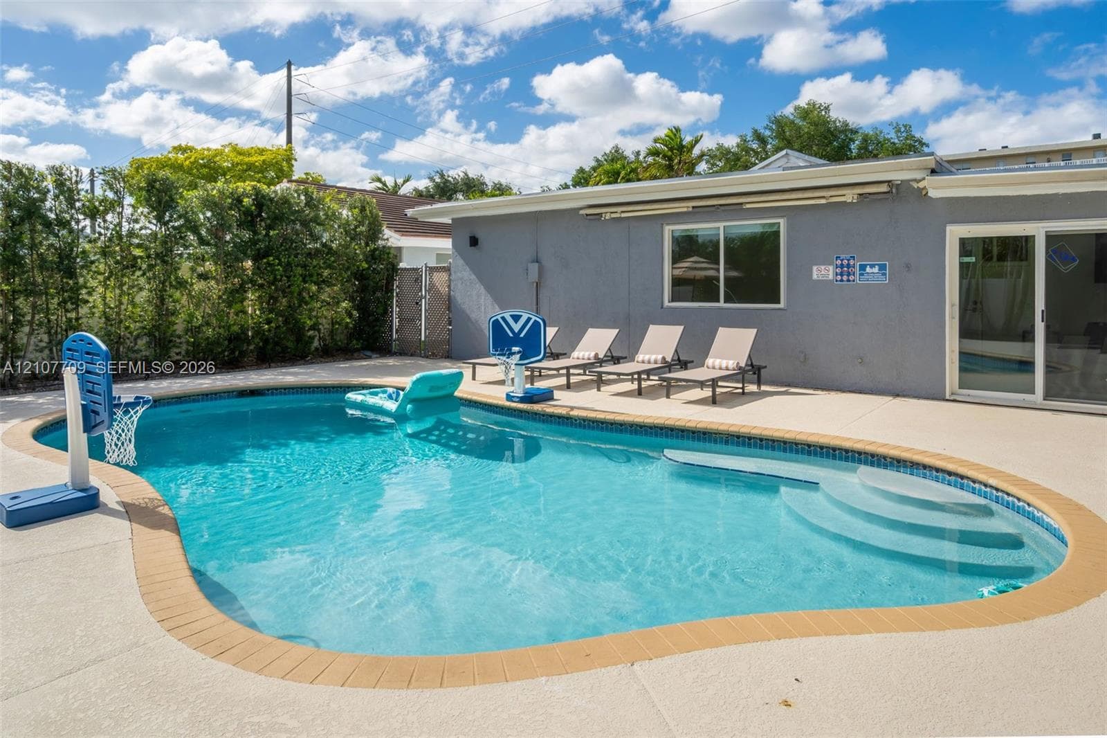 Inground swimming pool with tiled coping, integrated entry steps, and a surrounding concrete pool deck