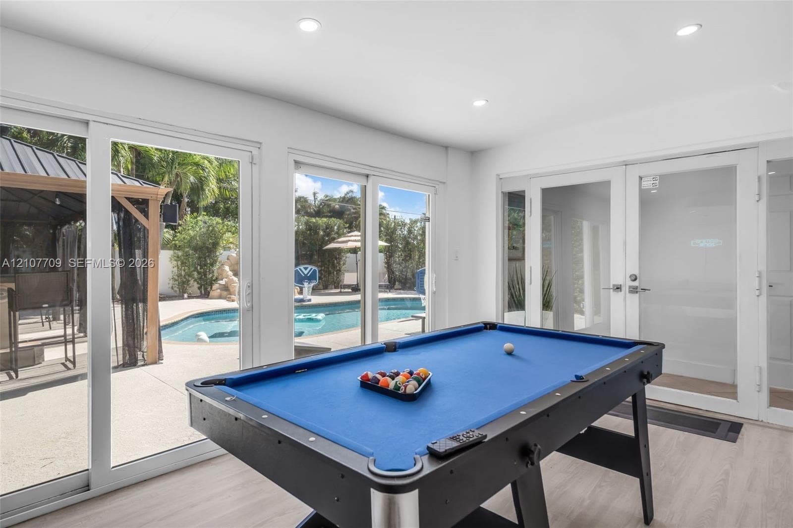 Bright interior space featuring recessed lighting, light-toned wood-finish flooring, full-height sliding glass doors, and glass-paned double doors