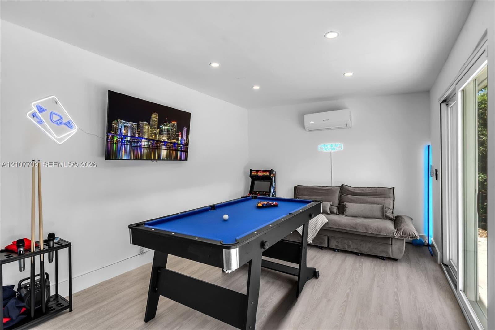 Neutral interior featuring wood-finish flooring, recessed lighting, wall-mounted ductless air conditioning unit, and sliding glass doors