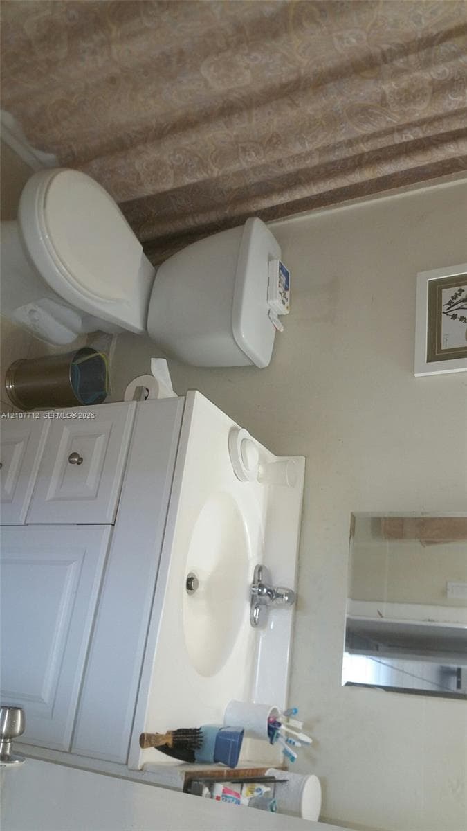 White vanity cabinet featuring an integrated sink, polished metal faucet, and a wall-mounted mirror