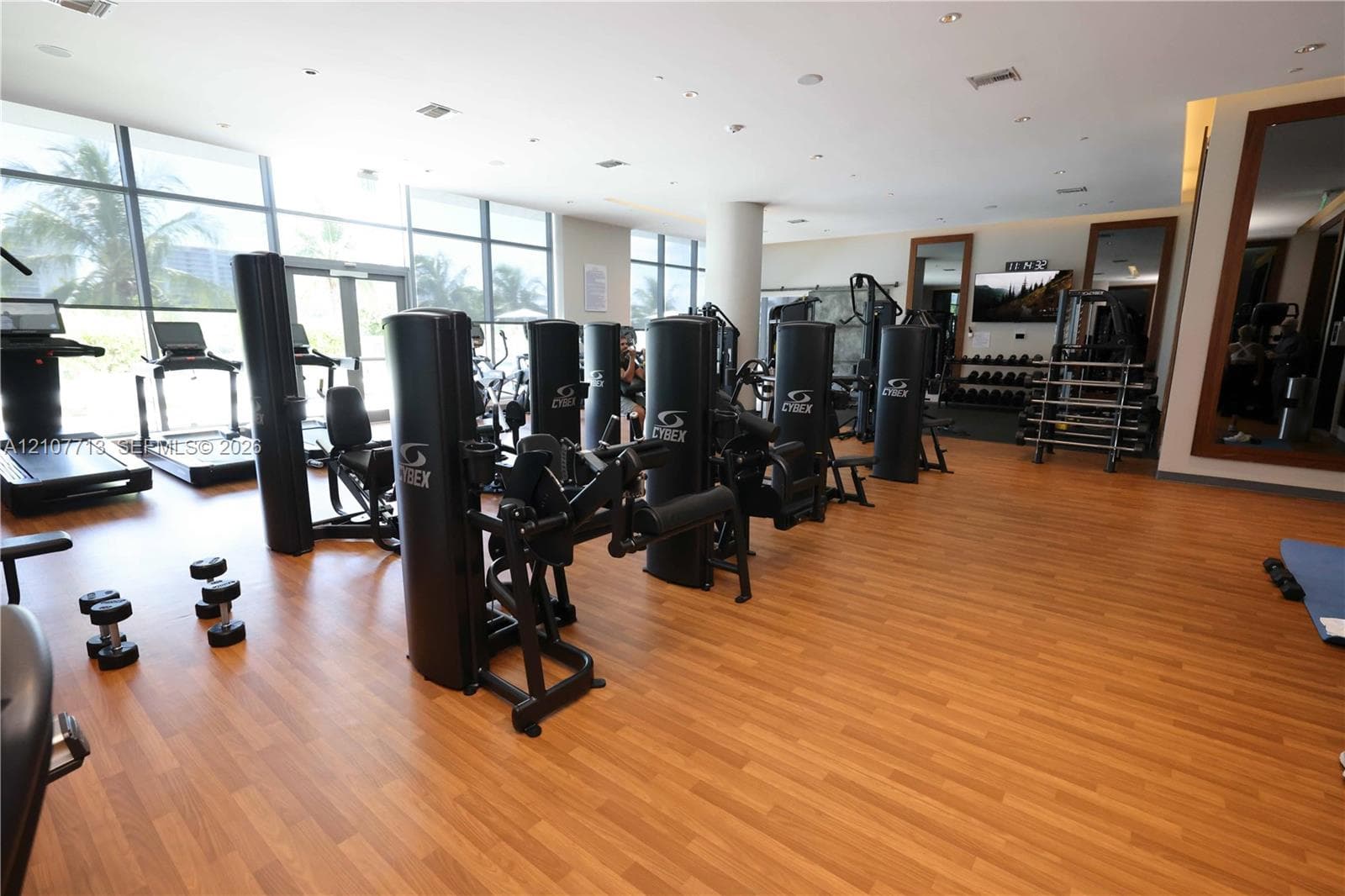 Fitness center featuring wood-finish flooring, floor-to-ceiling glass windows, recessed ceiling lighting, and large wall-mounted mirrors