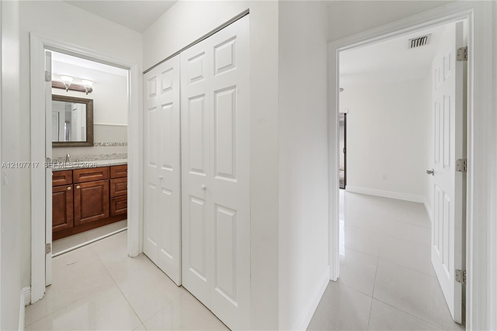 Hallway featuring tile flooring, dual-panel bifold closet doors, and solid-core interior doors