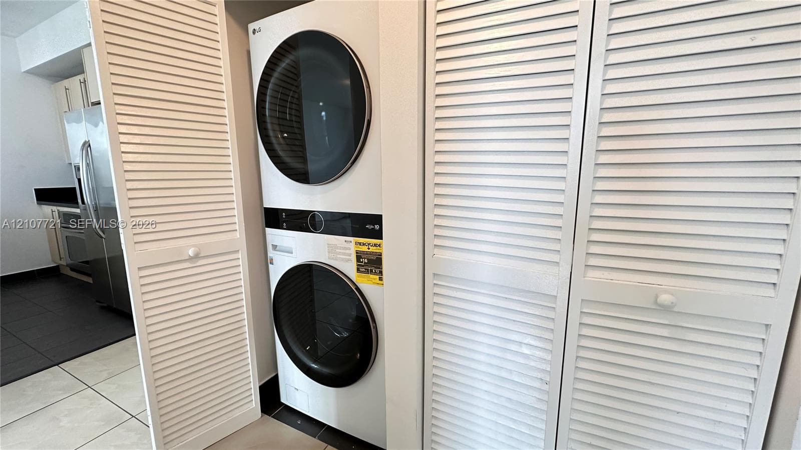 Stacked LG washer and dryer unit enclosed by white louvered doors