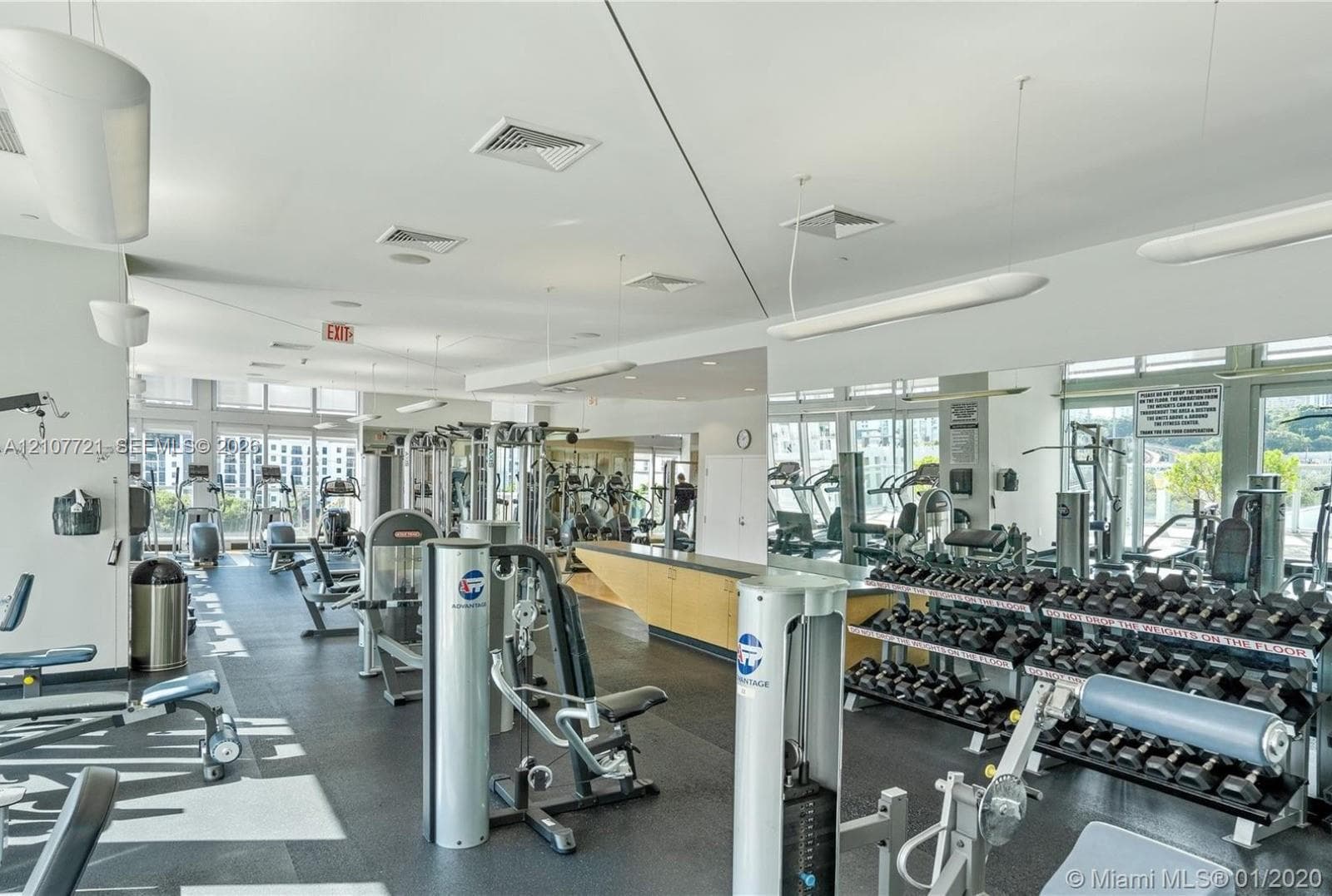 Fitness center featuring rubber flooring, floor-to-ceiling mirrored walls, recessed lighting, and expansive windows