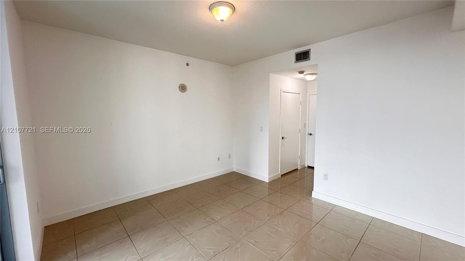 Interior space featuring neutral-toned tile flooring, white walls, and flush-mount ceiling lighting
