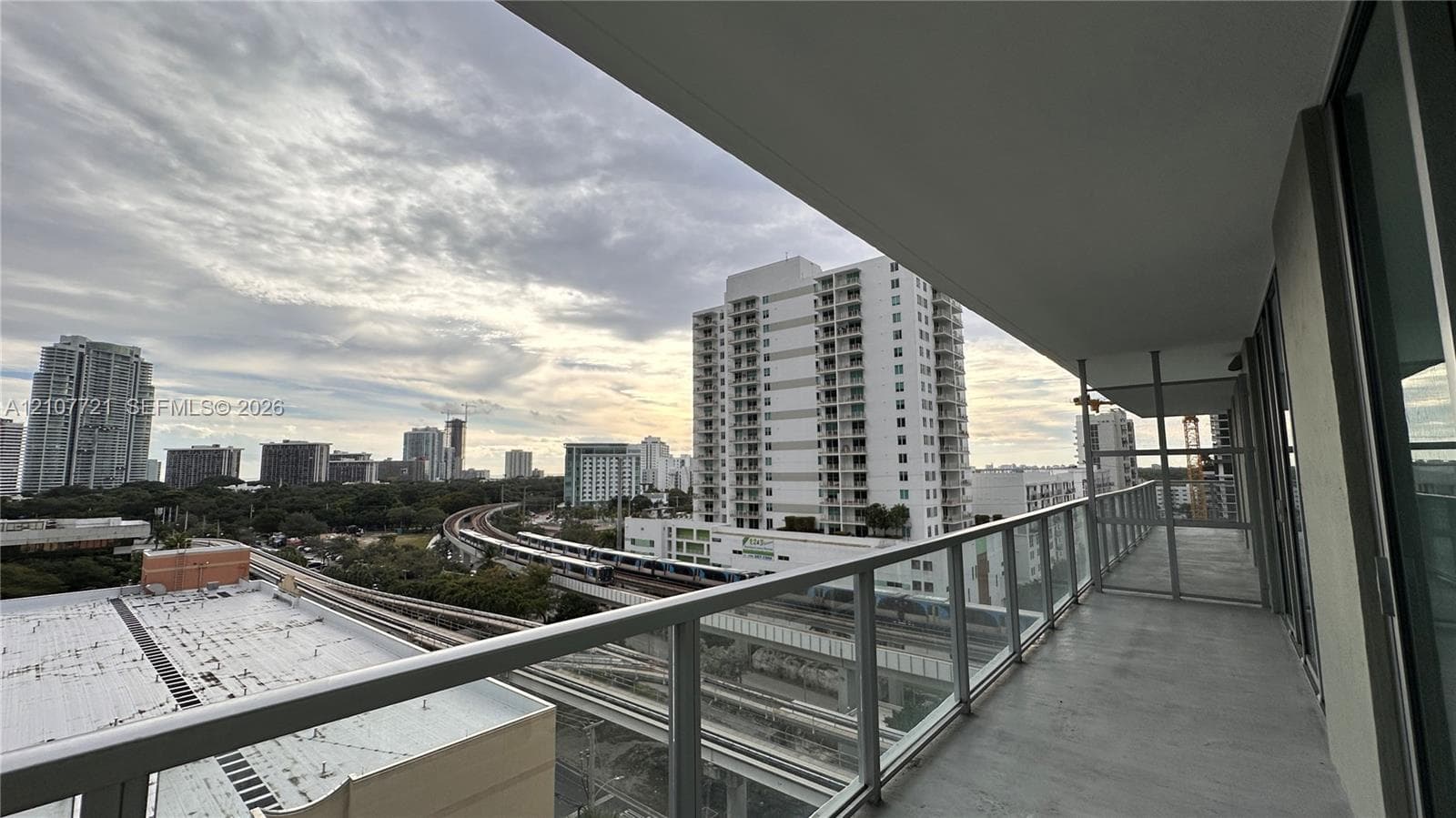 Covered balcony featuring concrete flooring and a glass-paneled metal railing