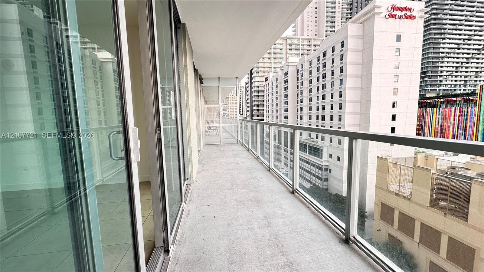 Private balcony featuring glass panel railings, concrete flooring, and full-length sliding glass door access