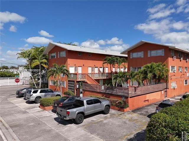 Two-story exterior featuring a horizontal slat privacy fence, second-level railed balcony, and exterior staircases