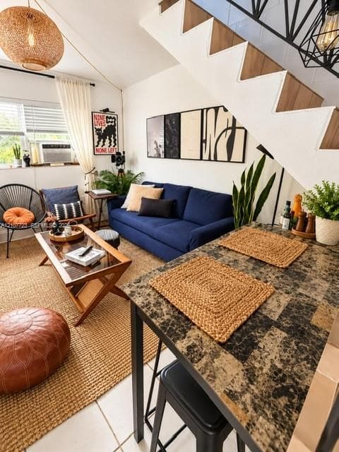 Open-plan living area featuring a staircase with black metal geometric railings, stone-tiled countertop, woven pendant lighting, and ceramic tile flooring