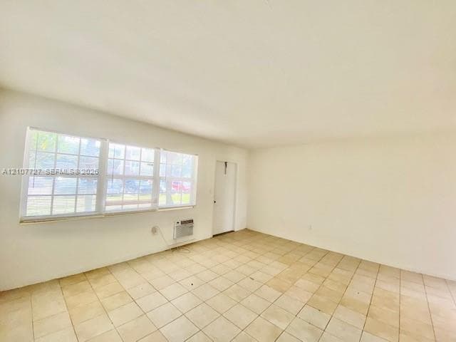Interior space featuring neutral wall tones, ceramic tile flooring, multi-pane windows, and a wall-mounted climate control unit