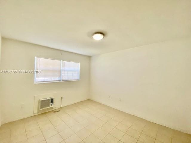 Neutral-toned interior space featuring ceramic tile flooring, a dual-pane horizontal window with blinds, and a built-in wall-mounted air conditioning unit