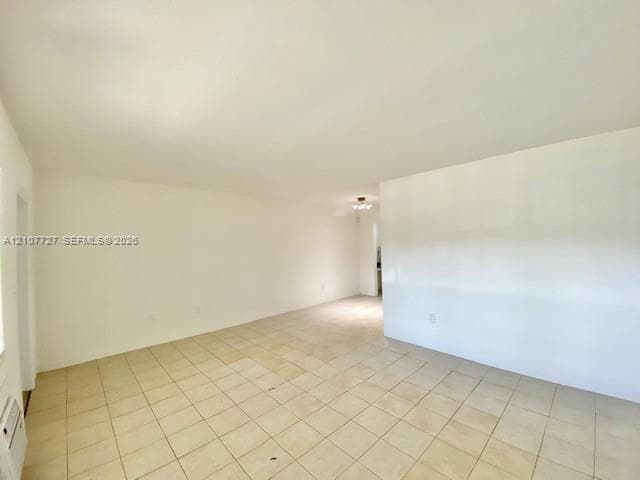 Spacious interior room featuring neutral wall finishes, tile flooring, and a flush-mount ceiling light fixture