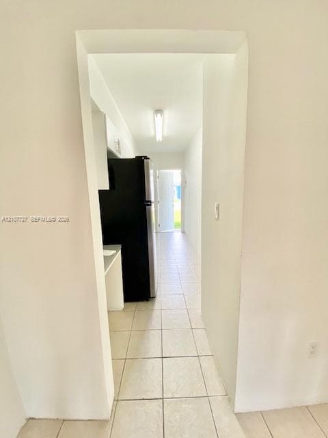 Ceramic tile flooring, white cabinetry, and a refrigerator with a stainless steel finish