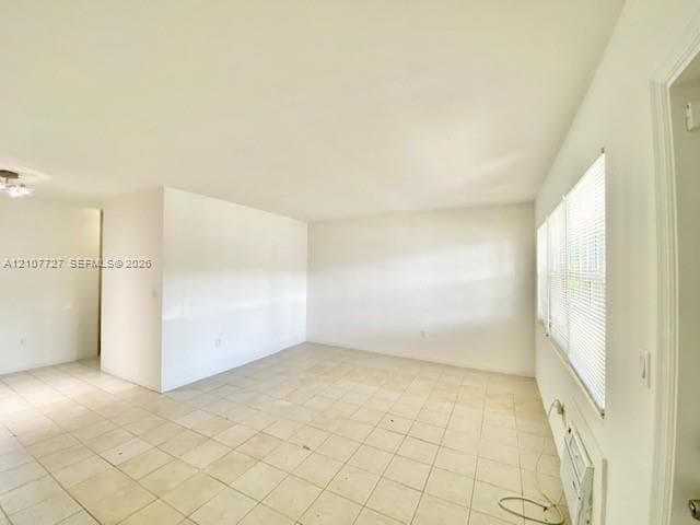 Neutral-toned tile flooring, white wall finishes, and multiple windows fitted with horizontal blinds