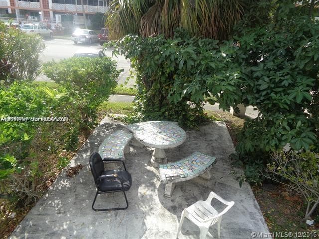 Stone patio area featuring built-in concrete mosaic-tiled circular table and curved seating benches