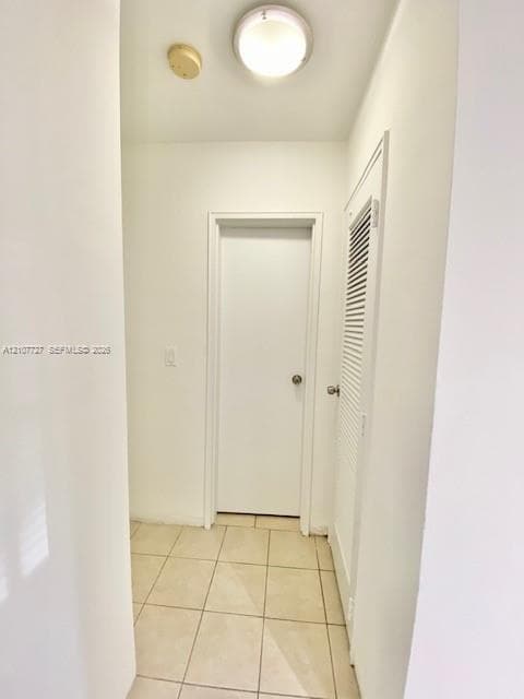 Neutral-toned tile flooring, flush-mount ceiling lighting, and a louvered closet door