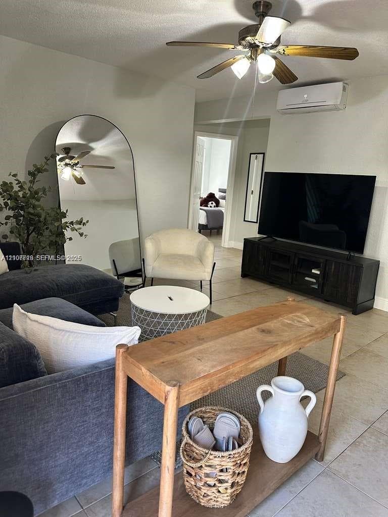 Neutral tile flooring, ceiling fan with integrated lighting, and wall-mounted ductless climate control unit