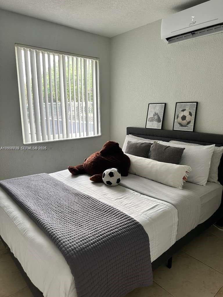 Wall-mounted ductless air conditioning unit, vertical window blinds, and neutral tile flooring