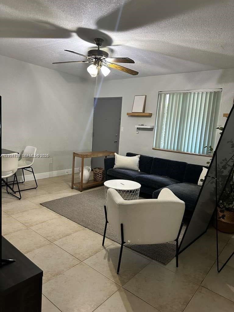 Neutral tile flooring, ceiling fan with integrated lighting, and vertical window blinds