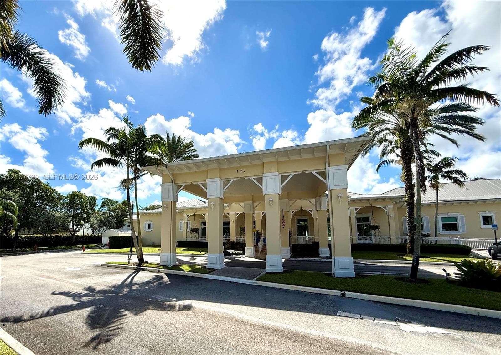 Covered porte-cochère entrance with decorative architectural brackets, exterior lighting fixtures, and mature palm landscaping