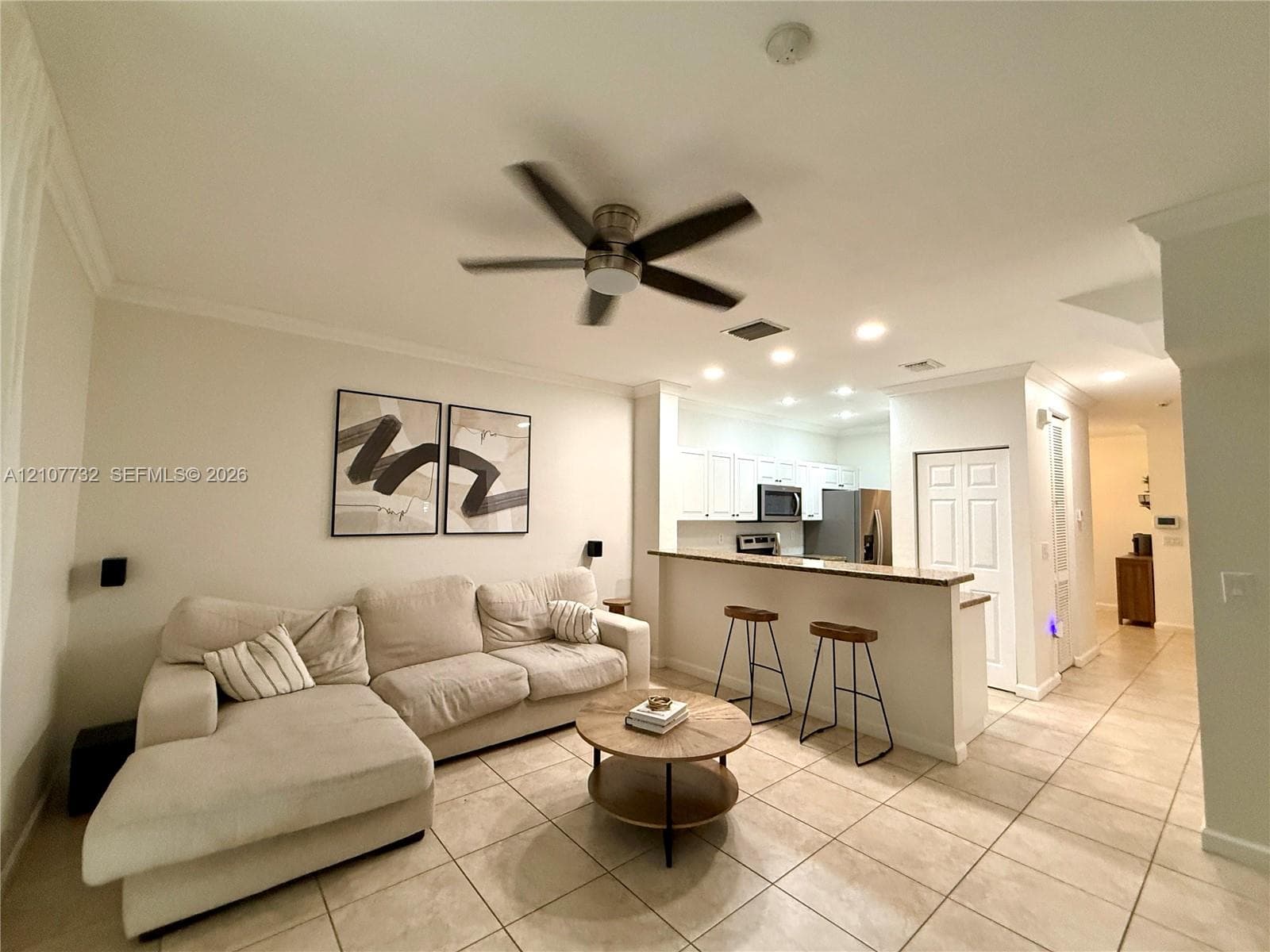 Open floor plan featuring tile flooring, ceiling fan, recessed lighting, and a kitchen breakfast bar