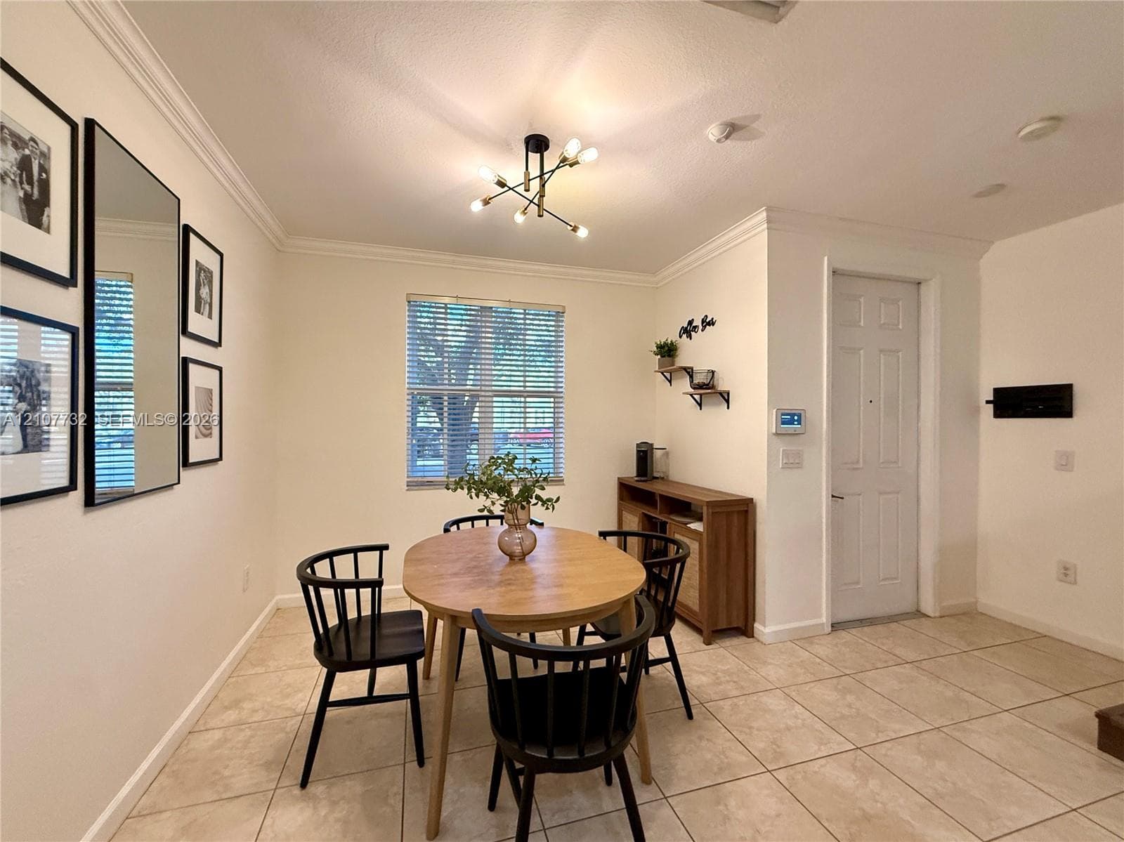 Neutral-toned tile flooring, crown molding, multi-arm geometric light fixture, and single-panel interior door