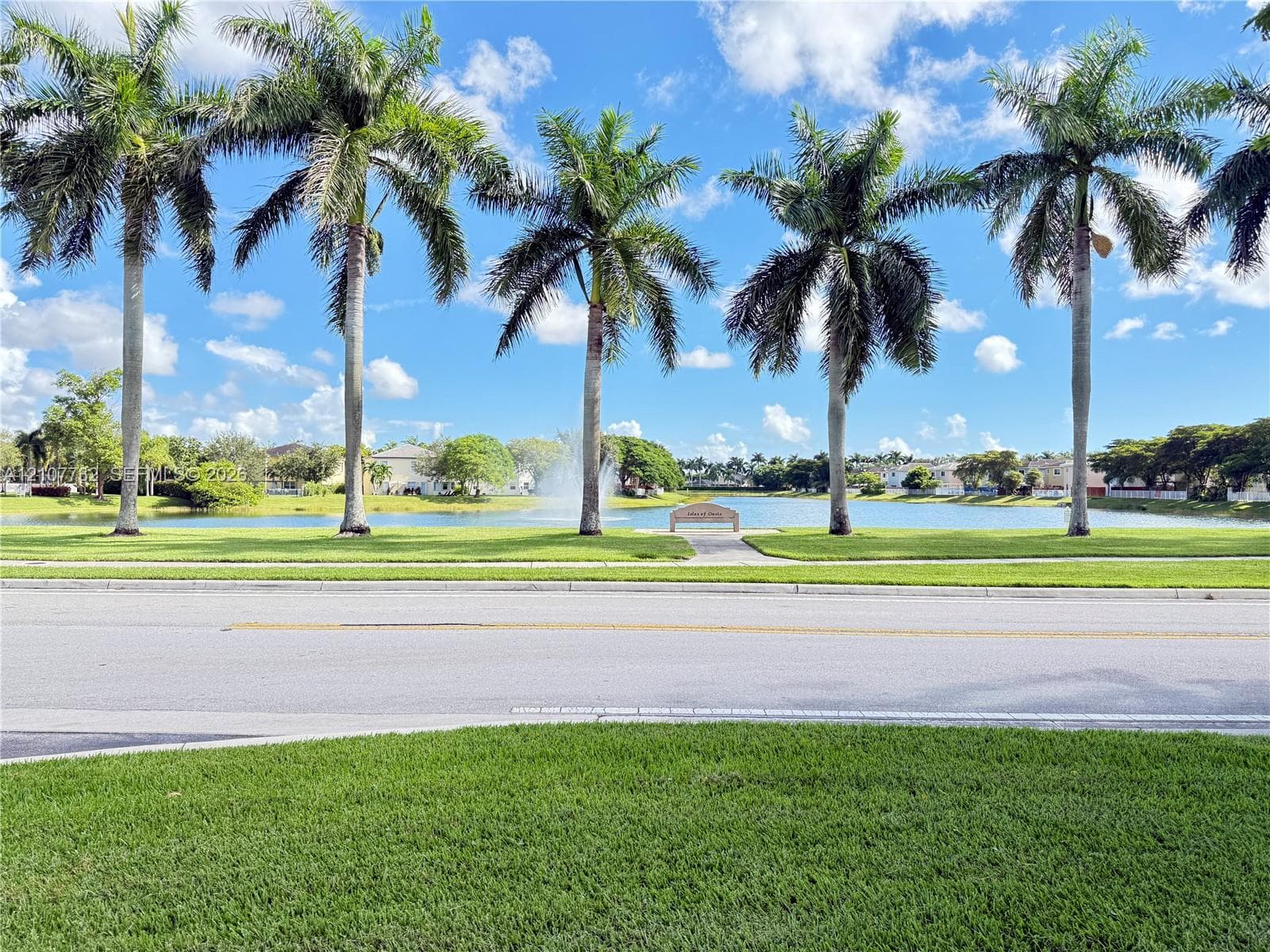Manicured lawn, mature palm trees, pond, and water fountain