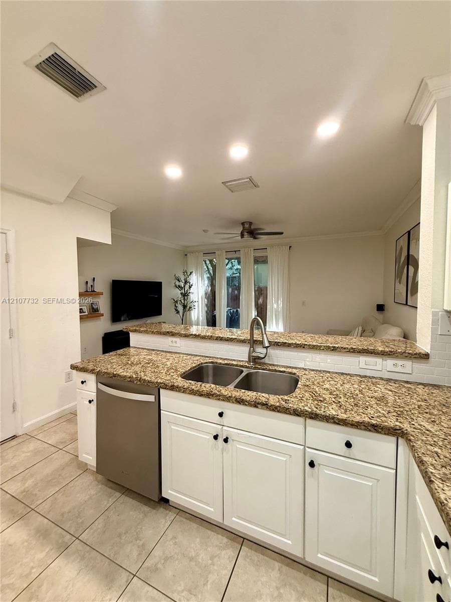 Kitchen featuring white cabinetry, stone-surface countertops, dual-basin stainless steel sink, recessed lighting, and tile flooring