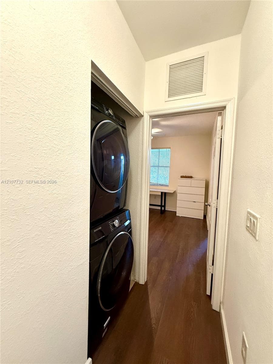Stackable laundry unit with high-gloss finish, wood-finish flooring, and crisp white wall paint