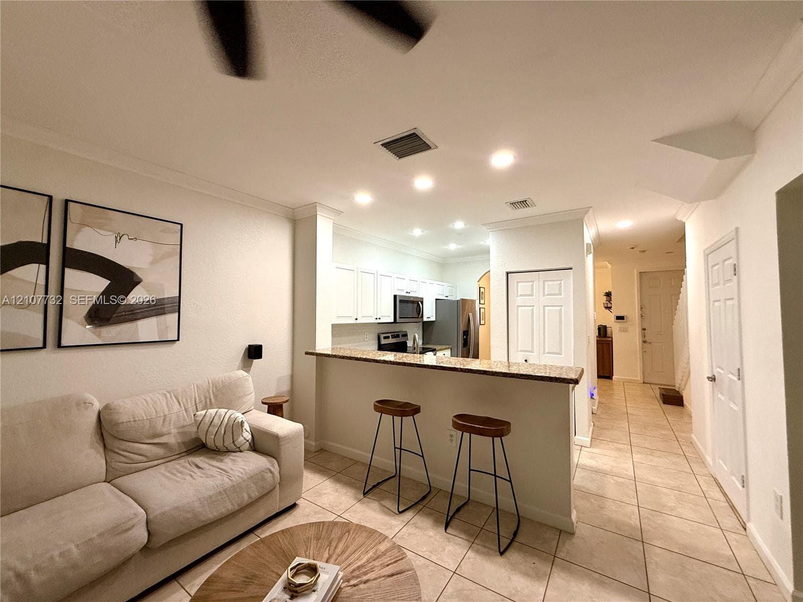 Kitchen featuring white cabinetry, a stone-surfaced breakfast bar, and recessed lighting