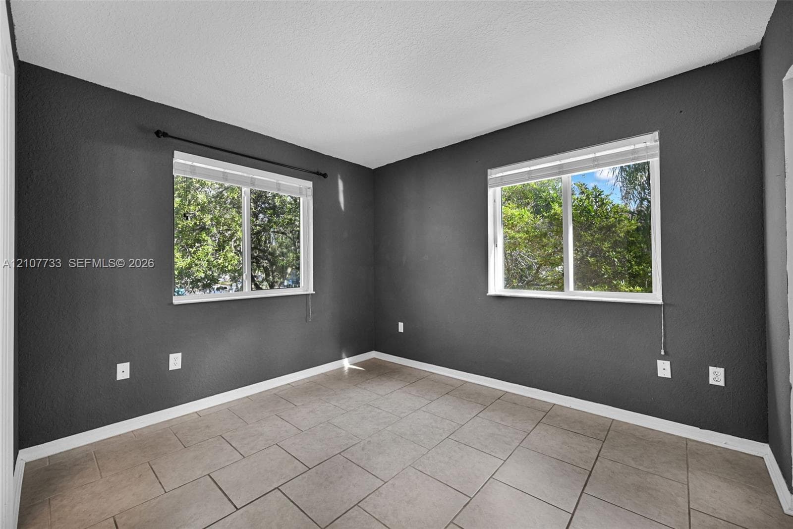 Room featuring dark-toned walls, tile flooring, and two windows with horizontal blinds