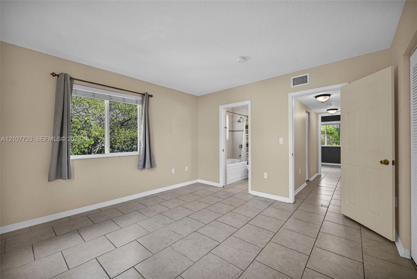Neutral-toned room featuring rectangular tile flooring, a horizontal sliding window, and interior paneled doors