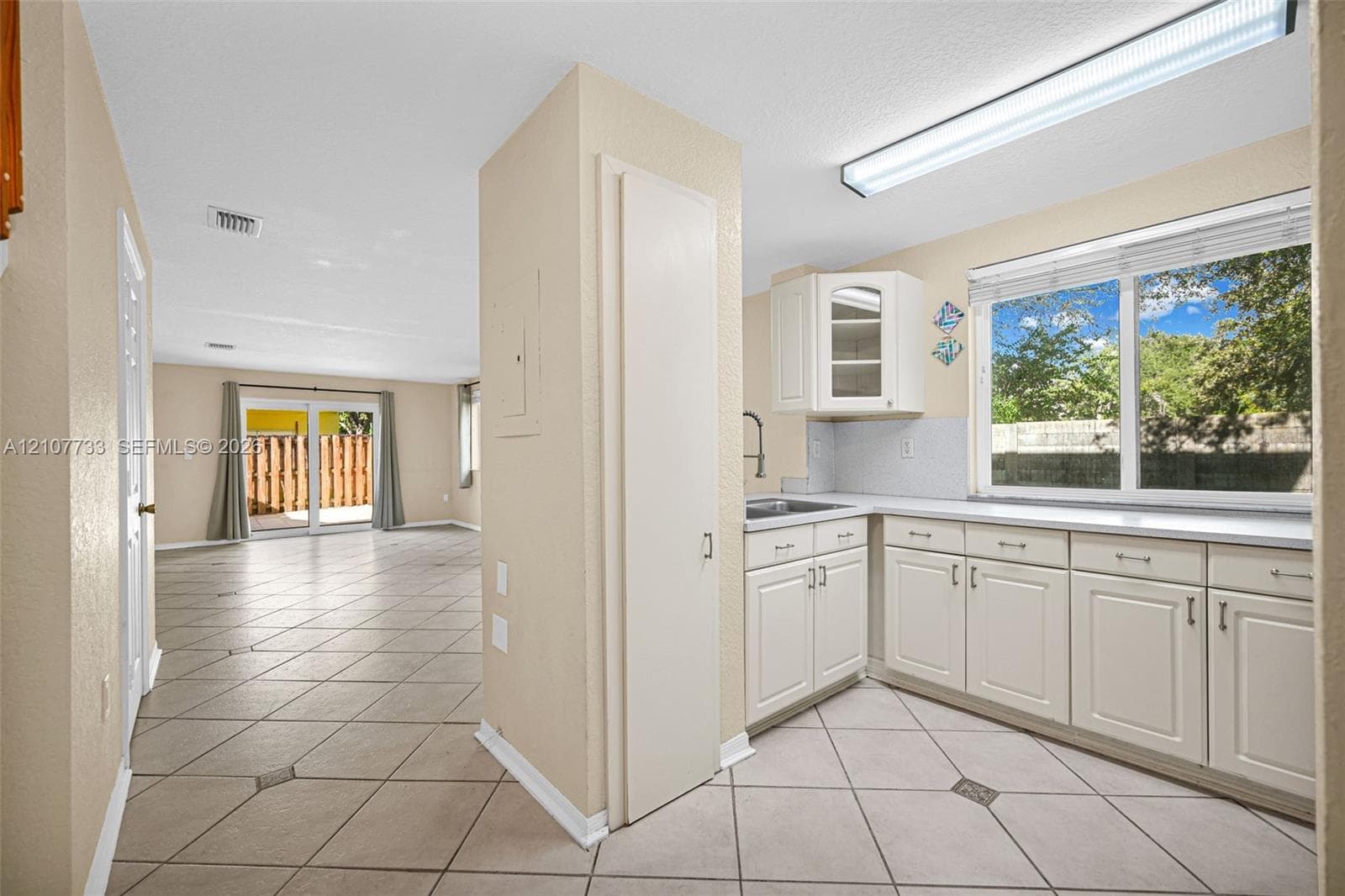 Kitchen featuring white cabinetry, solid surface countertops, and tile flooring with decorative inserts